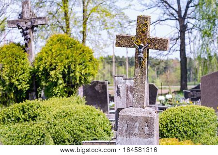Concrete old cross with crucifix in cemetery in summer.