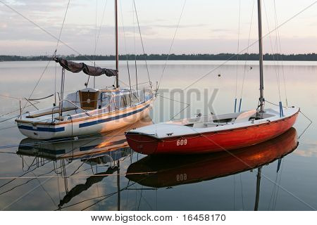 Sail boat anchored in bay at sunset