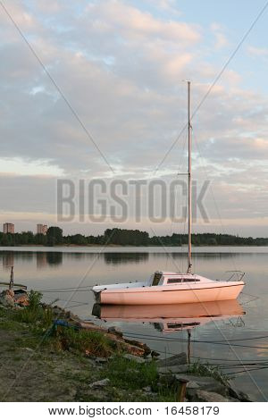 Sail boat anchored in bay at sunset