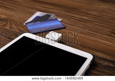 Credit card payment on a swipe or chip reader app on a tablet used by small or online businesses. The electronic device is used as a modern cash register or for banking.