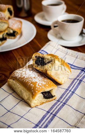 Baked sweet buns with poppy and coffee on wood table