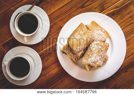 Baked sweet buns with poppy and coffee on wood table