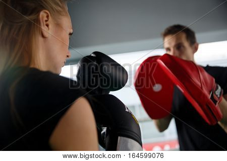 Young girl with man boxing at sports hall