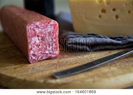 Big piece of cheese and salami. Wooden cutting board. Minimalistic picture.