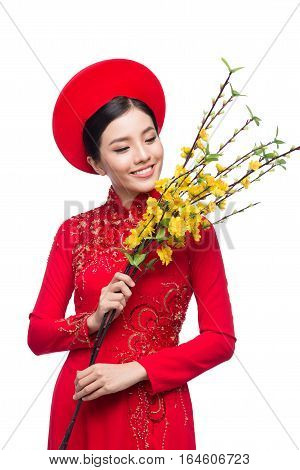 Portrait of a beautiful Asian woman on traditional festival costume Ao Dai holding Hoa Mai tree (Ochna Integerrima) flower. Tet holiday. Lunar New Year.