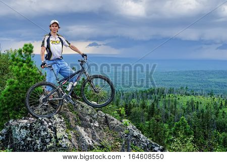 Oldman-Stone peak, Russia - July 28, 2007: Biker tourist in final point of a route. Around the dry tumbled-down trees. Height is 755 m. Sverdlovskaya region near Leviha