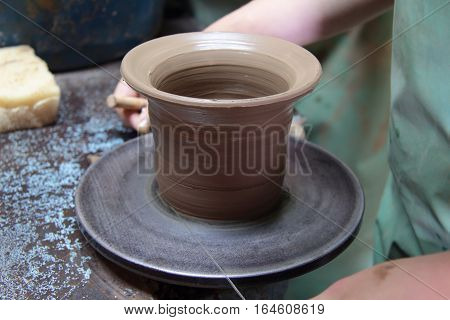 A clay pot on a pottery wheel, pottery craft, moulding the pot with your hands, sculpting hands