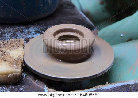 A clay pot on a pottery wheel, pottery craft, moulding the pot with your hands, sculpting hands