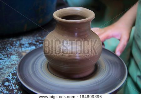 A clay pot on a pottery wheel, pottery craft, moulding the pot with your hands, sculpting hands