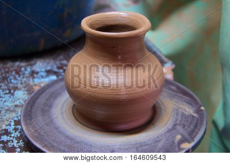 A clay pot on a pottery wheel, pottery craft, moulding the pot with your hands, sculpting hands