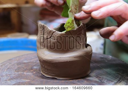A clay pot on a pottery wheel, pottery craft, moulding the pot with your hands, sculpting hands