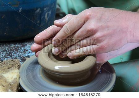 hands of a potter, creating an earthen jar on a pottery wheel