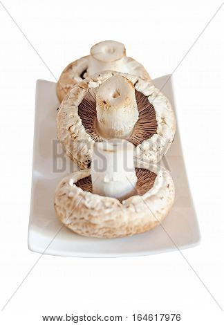 Mushrooms Champignon, Agaricus Bisporus On A White Plate, Close Up, White Background.