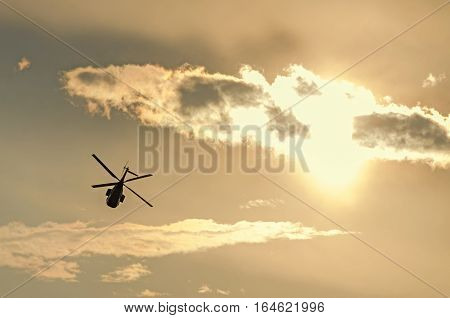 IAR Puma elicopter silhouette flying in the cloudy sky stunt aerobatic show sunset and sun rays.
