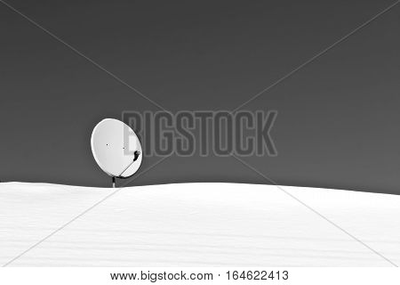 Sattelite Antenna On Snowy Roof In Black And White