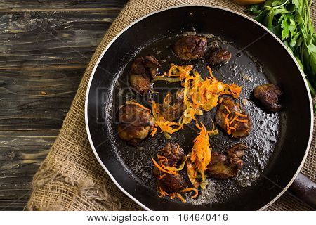 Fried chicken liver with vegetables in a frying pan