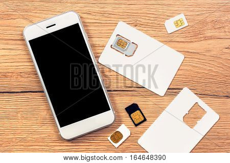 Smartphone with blank screen and SIM cards on the table top view