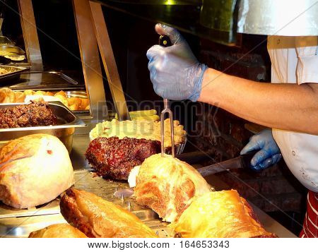 Chef carving roast beef and other meats at a buffet carvery