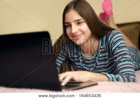 Young beautiful smiling woman using laptop computer lying on bed.