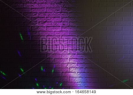 Textured brick wall lit by many colored lights