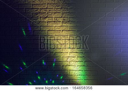Textured brick wall lit by many colored lights