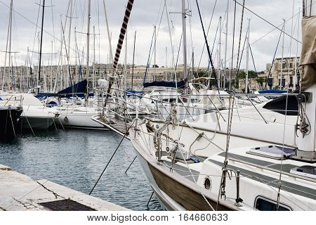 Yachts moored at Msida Marina in Malta. Sail boats in a row on docks at seaside harbor.