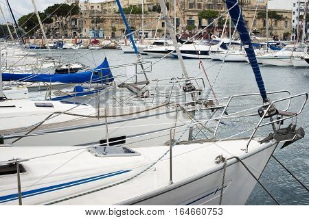 Yachts moored at Msida Marina in Malta. Sail boats in a row on docks at seaside harbor.