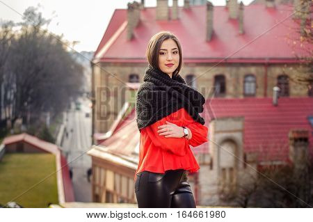 Portrait of a beautiful stylish woman in black leather pants on the background of the city