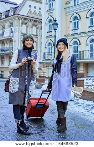 Two friends tourists are walking in old town with camera and map after arrival.