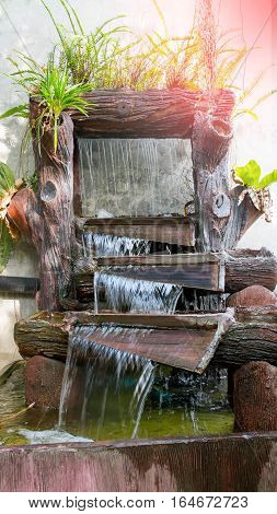 The beautiful nature in garden with waterfall on stone wall. Fountain decorated plants and ferns on stone