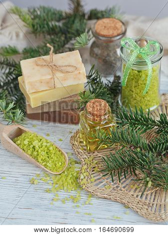 Natural sea salt and handmade soap with branch of pine on white wooden background. SPA concept.