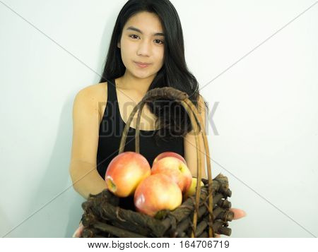 Asian woman holding red apple in wooden basket on white background focos on her face take on her side