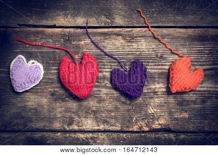 Valentine's Day. Colorful knitted hearts. Red heart on the dark old boards. Valentines day. Heart pendant. Red heart. Valentine cards. Eighth of March. International Women's Day. Toned image.