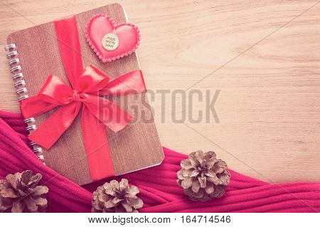 notebook wrapped with red ribbon red felt hearts in vintage pink color tone all on wooden table good for valentine or special occasion