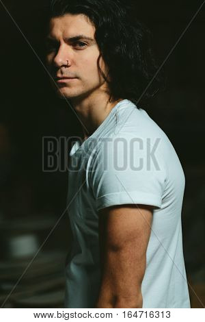 Portrait of a beautiful brutal guy with long hair on a dark background