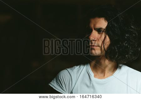 Portrait of a beautiful brutal guy with long hair on a dark background