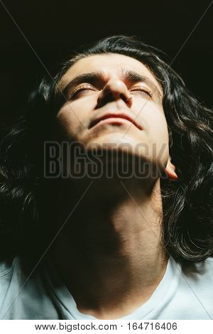 Portrait of a handsome young man with long hair looks up closeup