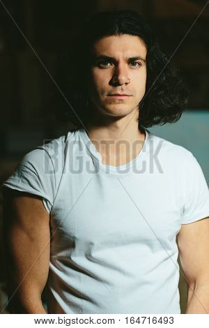 Portrait of a beautiful brutal guy with long hair on a dark background