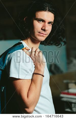 Successful young handsome guy with a denim jacket over his shoulder