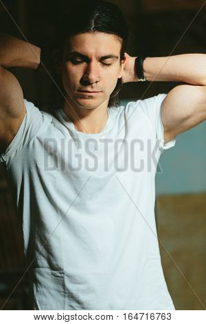 Portrait of a beautiful brutal guy with long hair on a dark background