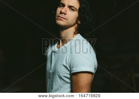 Portrait of a beautiful brutal guy with long hair on a dark background