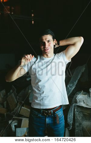Beautiful long-haired brunette guy hands behind his head in white t-shirts