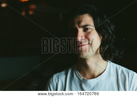 Beautiful long-haired brunette smiling man in a white T-shirt