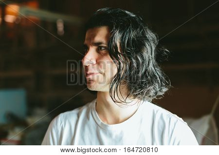 Beautiful long-haired brunette smiling man in a white T-shirt
