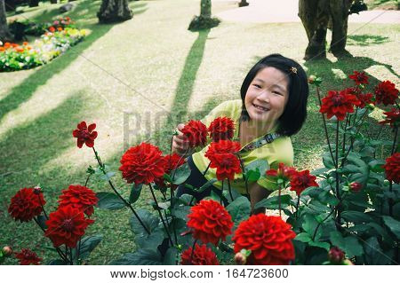 girl enjoy beautiful red dahlia in garden