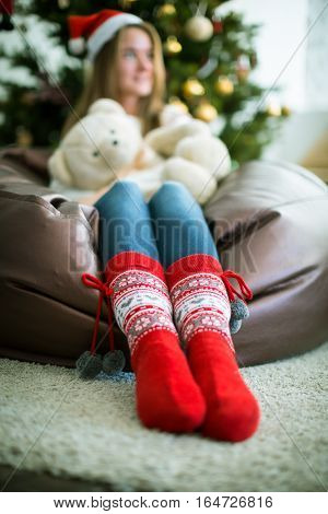 Close up of legs in bright red Christmas socks and defocused girl on background