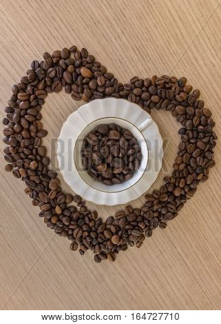 Coffee cup and coffee beans on a wooden table and heart shape made from coffee beans