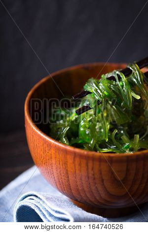 Wooden bowl with chuka salad on the dark background