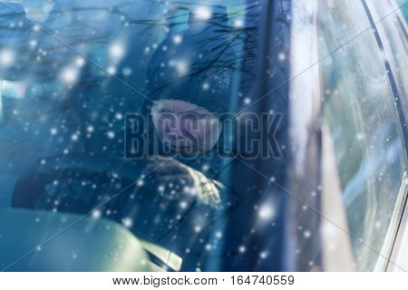 Young adult caucasian woman can not start car on cold snowy winter day