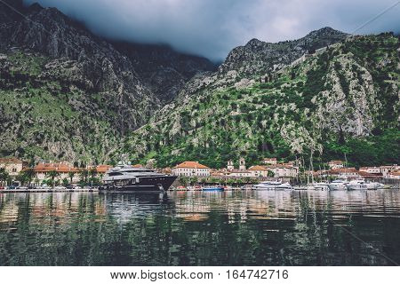 June 3th, 2016 - Kotor, Montenegro. Famous ancient Kotor City on Kotor bay by cloudy day in Montenegro. View to Kotor Old Town roofs, mountains and boats reflected on water of Boka Kotorska.
